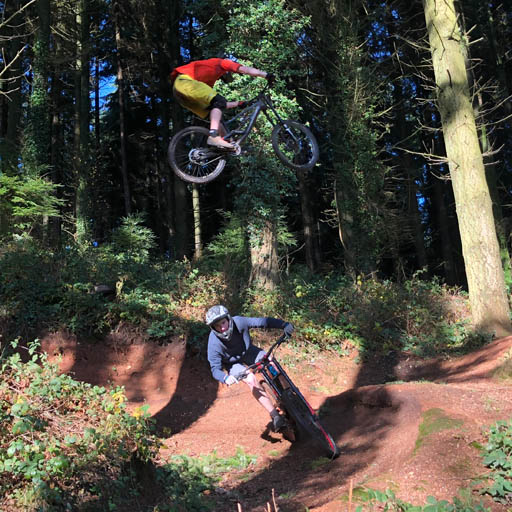 One mountain biker just casually jumping over another